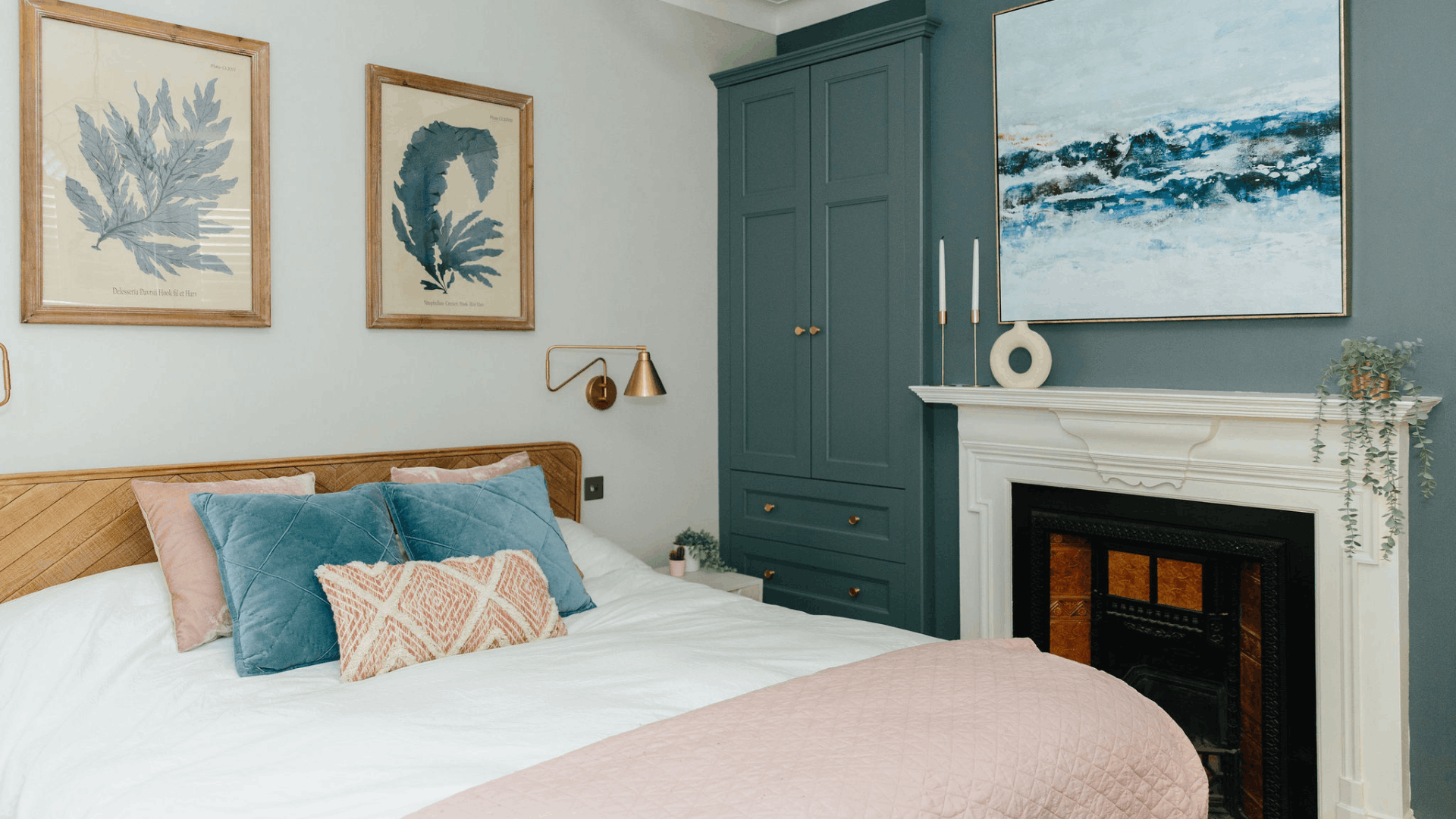 Small bedroom with built-in blue wardrobes, a white fireplace, and wooden bed frame.