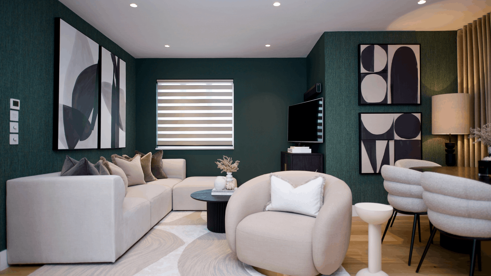 Living room with a low ceiling, teal walls, cream corner sofa and a cream rounded armchair.